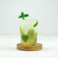 Mojito lemonade cocktail featuring fresh mint leaves and lime slices served over ice in a clear cup on a wooden coaster, perfect for a summer afternoon