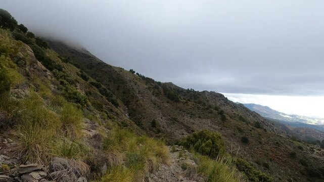 Fog and clouds on hiking trail to Maroma peak in thunderstorm day, Sierra Tejeda, Spain 