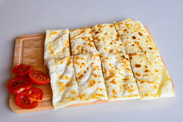 Freshly baked appetizing Turkish tortillas - Gozleme with spinach, cheese  on a white board. Space for text. Handmade Turkish traditional pastries. Ispanakli, otlu peynirli gozleme. Tahinli Katmer
