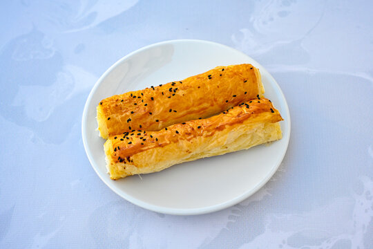 Turkish style meat stuffed filo dough borek served kol boregi. Cheese and minced pie are sliced on a marble background.  Avci boregi.Turkish name: Kol Boregi. Kiymali, peynirli su boregi.