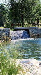 Tranquil waterfall cascading over a stone dam in a serene natural setting. Possible use Nature, peace, relaxation