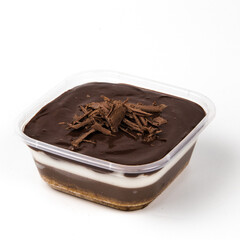 Layers of rich chocolate pudding cake and creamy filling topped with chocolate shavings sit in a clear container against a white backdrop