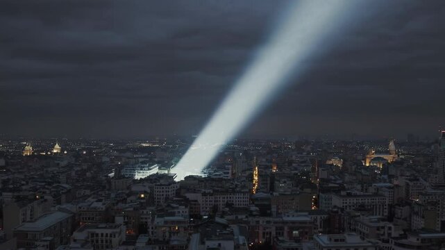 Bright searchlight illuminates city skyline during nighttime event in downtown area