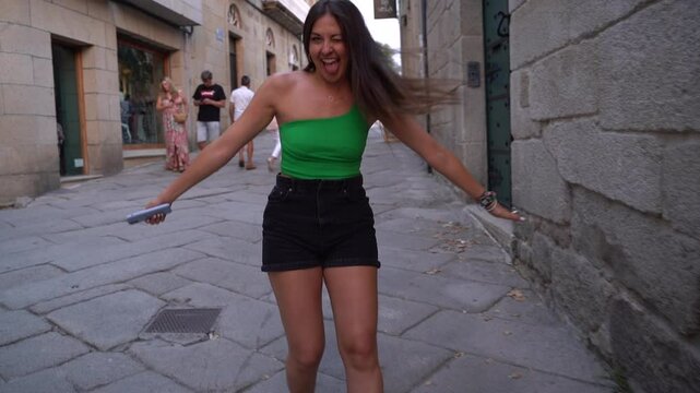 beautiful tourist girl walking forwards in the streets of Spain looking to camera