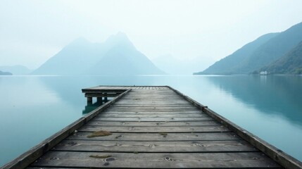 Serene Wooden Dock Extending to Misty Mountains Across Calm Water