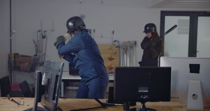 Rage room, anger and people with computer destruction for stress relief, emotional therapy and technology vandalism. Man, safety gear and smash pc with baseball bat for frustration and vent activity