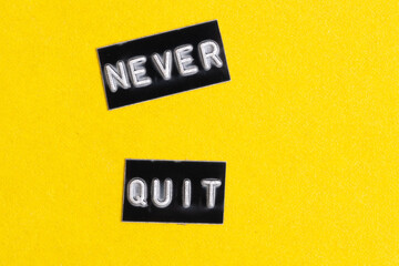 Word never quit in black letters on yellow background.