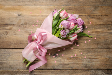 Bouquet of beautiful tulip flowers and pink paper hearts on wooden table, top view
