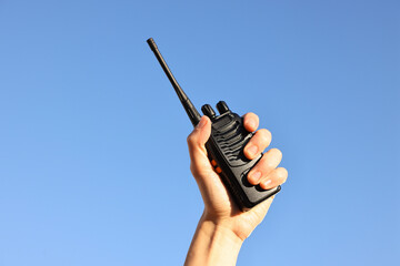 Woman with walkie talkie against blue sky outdoors, closeup
