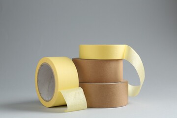 Rolls of different adhesive tapes on grey background