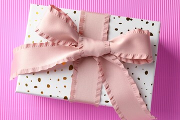 Gift box with beautiful bow on pink background, top view