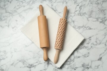 Rolling pins and napkin on light marble table, flat lay