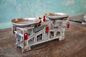 Vintage weighing scale rests gently on a rustic wooden table against a faded wall, capturing the...