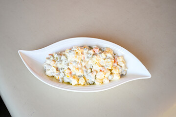 Bowl of russian salad olivier with meat and vegetables on a table