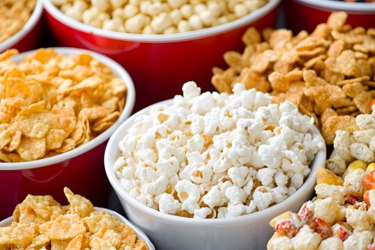 Popcorn and Cereal Variety: A close-up shot showcasing an assortment of breakfast cereals and freshly popped popcorn in small bowls, highlighting textures and colors.  The image is perfect for blogs. - Powered by Adobe