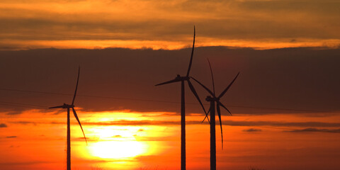 Wind power plant landscape at sunset time with dramatic sky.Wind farm at sunset. Pure energy, wind turbine. Wind turbines farm. Sunset Landscape.