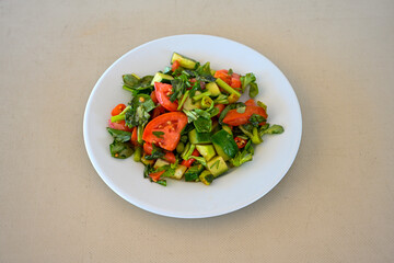 Green salad with arugula, lamb and tomatoes. Healthy vegan dish. Top view at table. Turkish Coban (choban) salata or Shepherds salad, Akdeniz salad in white bowl.
