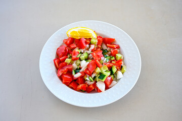 Green salad with arugula, lamb and tomatoes. Healthy vegan dish. Top view at table. Turkish Coban (choban) salata or Shepherds salad, Akdeniz salad in white bowl.