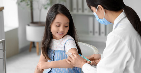 Fototapeta premium Little Asian girl receiving vaccine in clinic