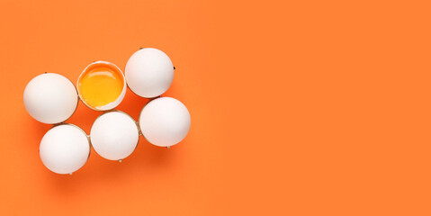 Holder with raw chicken eggs on orange background