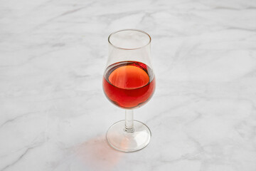 Glass of red brandy on a marble surface reflecting light with elegant simplicity