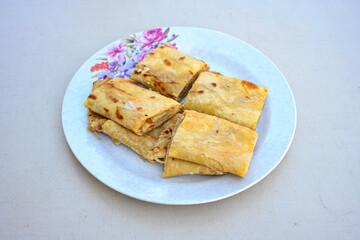 Freshly baked appetizing Turkish tortillas - Gozleme with spinach, cheese  on a white board. Space for text. Handmade Turkish traditional pastries. Ispanakli, otlu peynirli gozleme. Tahinli Katmer