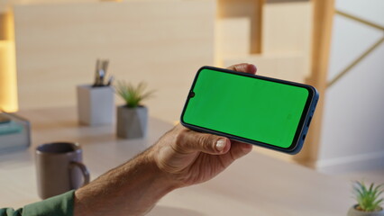 Guy holding horizontal mockup cellphone at creative agency workplace closeup. 