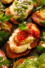Sweet potato toasts with various toppings, in the middle toast with bean paste and paprika sauce, close-up view.