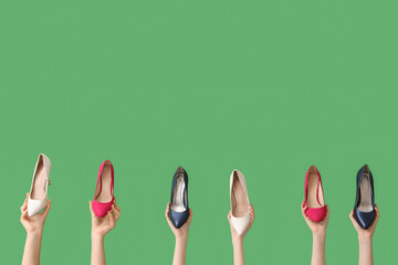 Women with stylish high-heeled shoes on green background