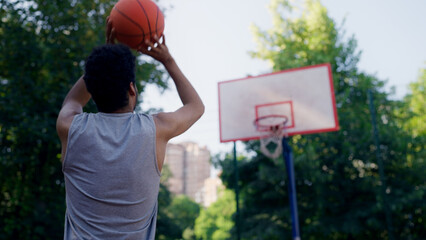 Back view of an African American guy throwing a basketball into the hoop, celebrating success