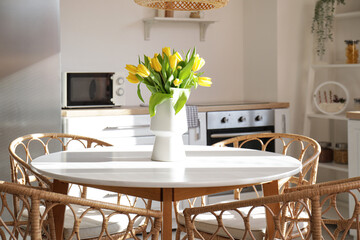 Beautiful vase of yellow tulips on dining table in kitchen