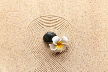 Stack of black stones and plumeria on sand with lines. Zen concept