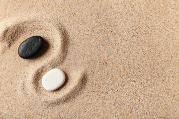 Black and white spa stones on light sand. Zen concept