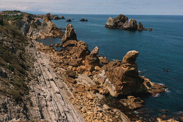 A dramatic coastal landscape with layered rock formations and rugged cliffs