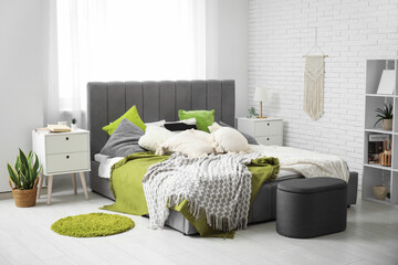 Modern bedroom with bed, bedside tables, pouf and shelving unit