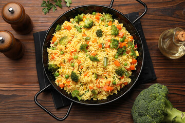 Tasty rice with vegetables served on wooden table, top view