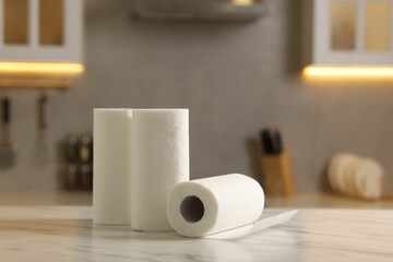 Rolls of paper towels on white marble table in kitchen, space for text