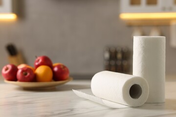 Rolls of paper towels and fruits on white marble table in kitchen