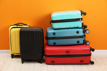 Many colorful suitcases on floor near orange wall