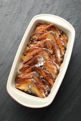 Freshly baked bread pudding in baking dish on grey textured table, top view