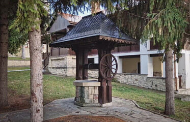 Naklejka premium Traditional old well made of wood and stone, in the Capriana monastery courtyard, Moldova.