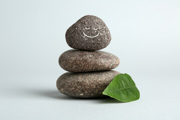 Stack of rocks with drawn smiley face on light grey background. Harmony and life balance