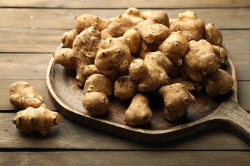 Raw Jerusalem artichokes on wooden table, closeup