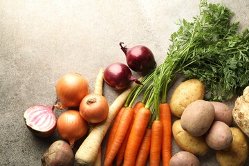 Different root vegetables on grey table, flat lay. Space for text