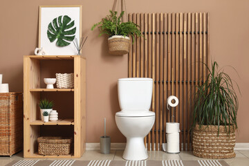 Ceramic toilet bowl, shelving unit and plants in interior of restroom