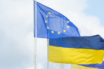 The flags of Ukraine and the European Union flutter against the sky. The unification of Europe.