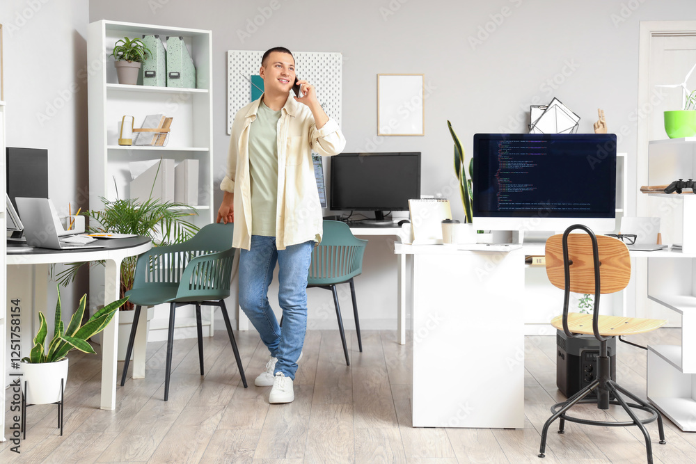 Wall mural handsome programmer talking by mobile phone in office