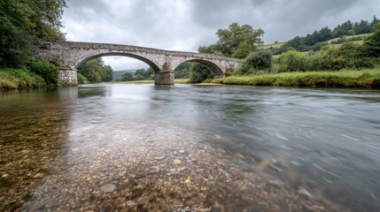 Fototapeta premium Tranquil river scene with historic bridge scenic nature landscape photography overcast sky serene environment peaceful concept