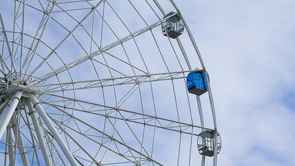 A majestic Ferris wheel stands tall against a clear blue summer sky