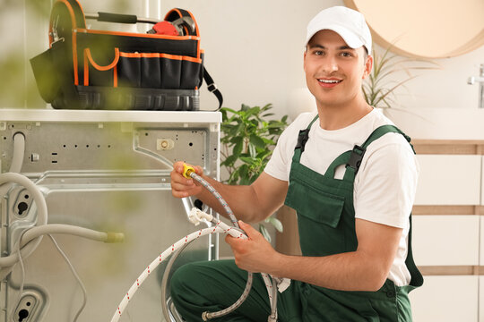 Male plumber fixing washing machine in bathroom